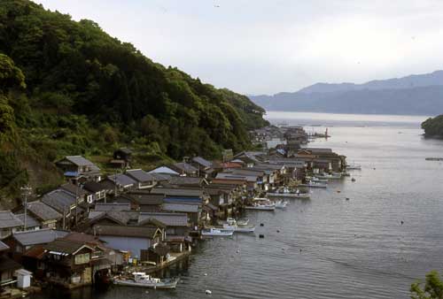 切妻屋根が海に向かっている舟屋群の家並みの写真