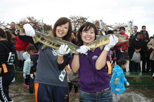 つかみどりした鮭を手に笑顔の参加者の写真