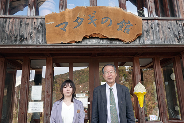 マタギの郷交流館の前で。生源寺塾長（右）と小松佳帆里さん（左）