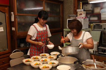 女将とともに夕食の準備をするインターン生の写真