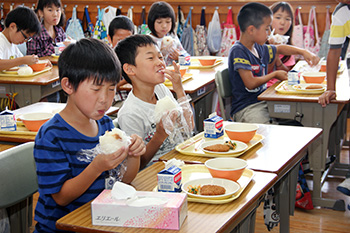 梅干しおにぎりをほおばる小学生の写真