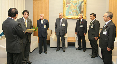 安倍官房長官（左から2人目）・山本会長（中央）の写真
