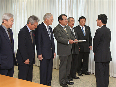 神野委員長（右）から中間報告を受け取る麻生知事会長の写真